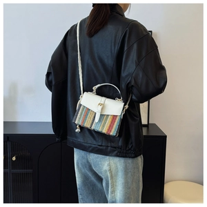 Dettaglio di una borsa a tracolla intrecciata colorata indossata da una modella