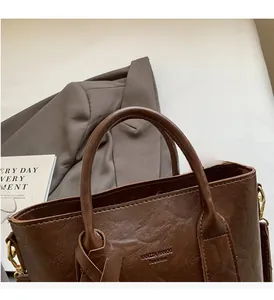 Détail d'un sac à main en cuir marron foncé avec logo embossé sur fond de blazer vintage