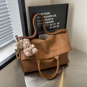 Brown faux leather tote bag with plush bear charm and adjustable shoulder strap