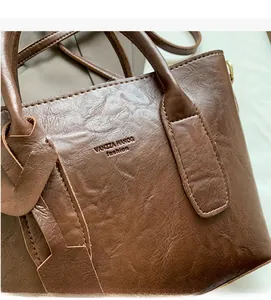 Détail du sac seau en cuir marron avec logo embossé et finitions dorées chic