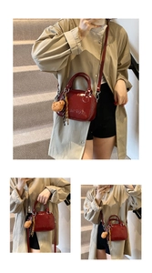 Model showcasing a burgundy glossy leather crossbody bag with a plush bear charm on stairs