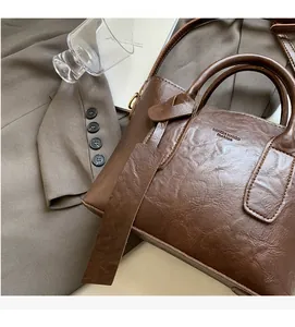 Gros plan d'un sac à main en cuir marron vintage avec texture naturelle et logo VANNZZA