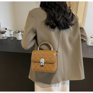 Photo lifestyle d'un sac à bandoulière matelassé marron porté avec un blazer marron chic
