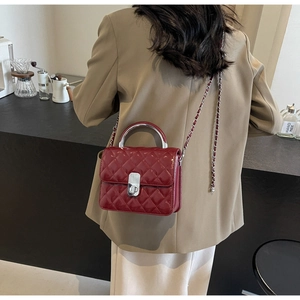 Détail du sac bandoulière matelassé bordeaux avec chaîne argentée et poignée en métal