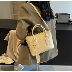 Détail d'un sac seau crème avec pendentif noué et bandoulière fine en similicuir souple