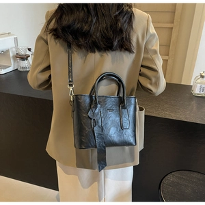 Vue détaillée du sac à main noir en cuir texturé avec crochets métalliques sur modèle