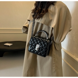 Détail du sac bandoulière matelassé noir avec poignée argentée et chaîne sur le mannequin