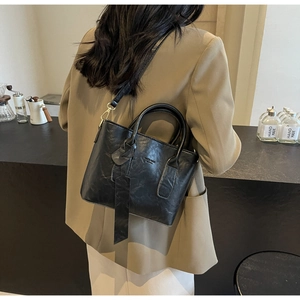 Détail d'un sac seau chic en cuir PU noir sur un comptoir de café au style minimaliste