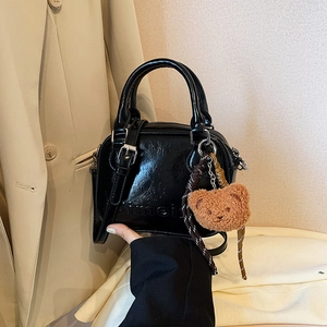 Minimalist black patent leather handbag with embossed letters and a bear keychain charm