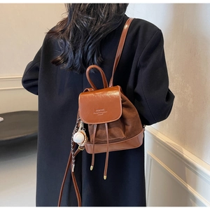 Détail d'un mini sac à dos vintage avec rabat en cuir brillant et texture suédine