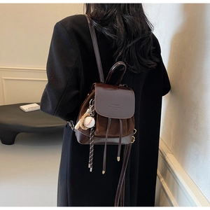 Détail macro du mini sac à dos en cuir marron foncé avec pendentif de baseball vintage