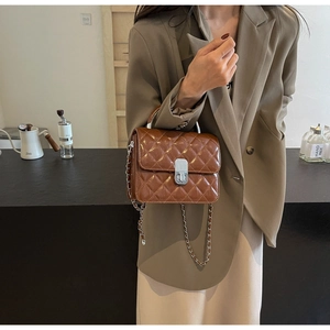 Détail du sac matelassé marron avec bandoulière chaîne argentée et poignée en métal