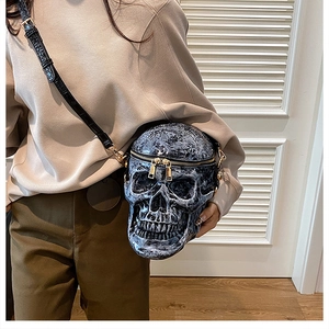 Skull crossbody bag shown on model featuring distressed texture and gold zipper detail