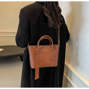Grand sac cabas marron porté sur un manteau noir pour montrer la taille réelle