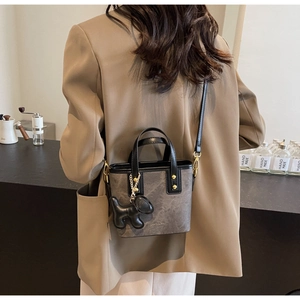 Detail der dunkelgrauen Bucket Bag mit schwarzen Griffen und Hundeanhänger an der Schulter