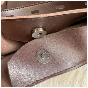 Detail of dark brown pebble leather bag featuring silver magnetic snap closure