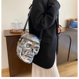 Detailed view of silver skull crossbody bag with gold zipper worn on a black suit