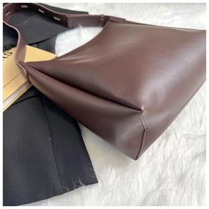 Detailed view of the dark brown leather tote bag with adjustable strap on white faux fur