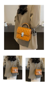 Détail d'un sac bandoulière matelassé jaune avec poignée métallique et chaîne sur mannequin