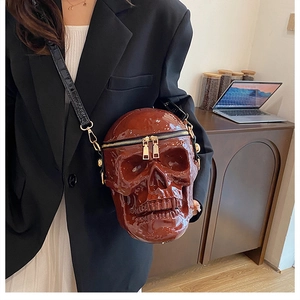 Detailed view of glossy dark brown skull crossbody bag with golden dual zippers
