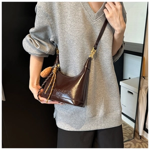 Detailed view of dark brown glossy underarm bag with Meiya logo and fuzzy ball charm