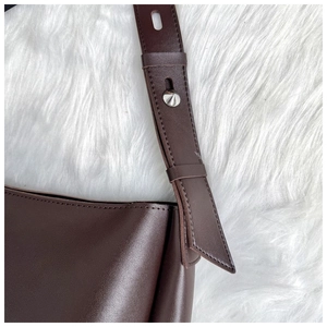 Detail of dark brown leather tote strap with fine stitching and silver buckle hardware