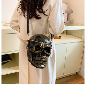 Detail shot of a creative skull crossbody bag in dark bronze with gold zipper on a model