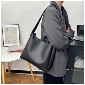 Minimalist black large capacity tote bag shown on model in a modern office setting