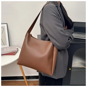 Model wearing a large vintage brown leather tote bag for a minimalist commuter style