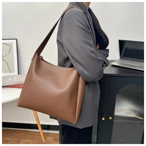 Brown leather tote bag side view on shoulder showing large capacity for work commuting