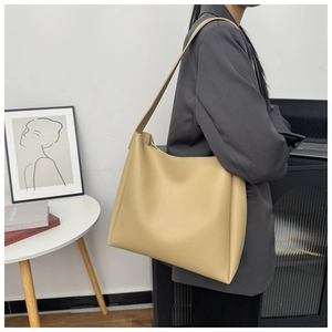 Detail of a large beige tote bag worn on shoulder, minimalist faux leather design