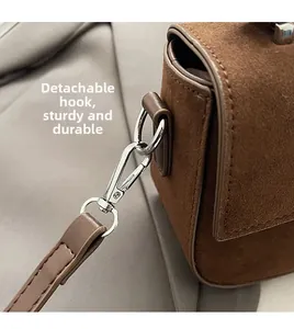 Détail d'un sac à main en daim marron foncé avec crochet métallique argenté amovible