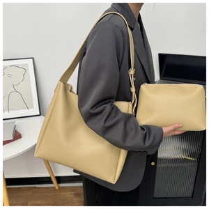 Beige oversized hobo tote bag and matching pouch shown on shoulder in office setting