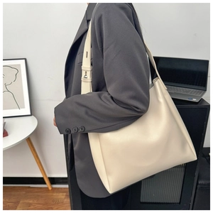 Detail of adjustable shoulder strap and smooth leather texture of beige tote bag