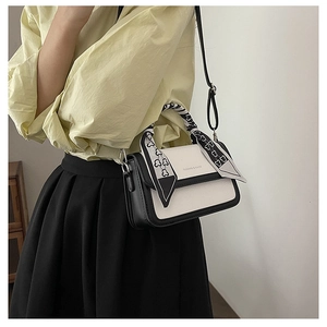 Detail of color-block crossbody bag with heart-print ribbon wrapped around handle