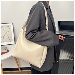 Minimalist cream leather tote bag with adjustable strap shown in a modern office setting