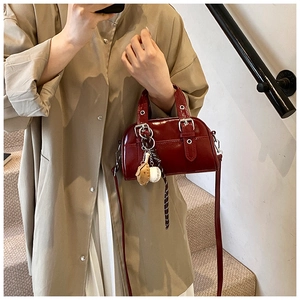 Détail du sac en cuir verni bordeaux avec breloque baseball et boucles argentées