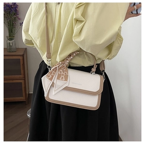 Chic beige crossbody bag with silk ribbon detail shown in lifestyle fashion photography
