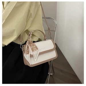 Detail of crossbody bag with litchi grain texture and bear print silk ribbon handle