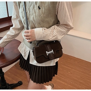 Détail du petit sac bandoulière en daim marron foncé avec boucle en H argentée et poignée