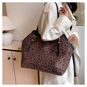 Vista dettagliata della borsa tote leopardata con tracolla nera indossata su cappotto bianco