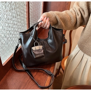 Dettaglio borsa nera lucida in ecopelle con tracolla e ciondolo a forma di mini borsa
