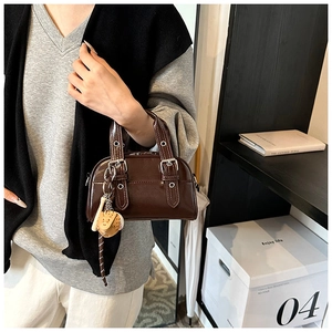 Détail du sac Boston vintage marron foncé avec sangles en cuir, rivets et breloque baseball