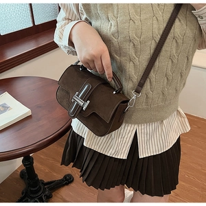 Gros plan d'un sac bandoulière en daim marron avec boucle en métal argenté poli