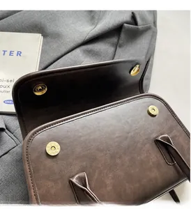 Close-up of vintage brown leather bag with dual magnetic buckles and gold hardware