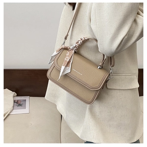 Detail of lychee textured leather crossbody bag with silk scarf handle and metal ball