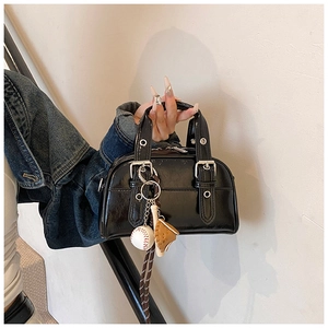Détail du sac en cuir verni noir avec ferrures argentées et breloques de sport