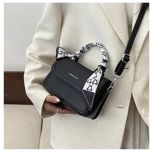 Detail of black textured crossbody bag with printed silk ribbon and fashion lettering