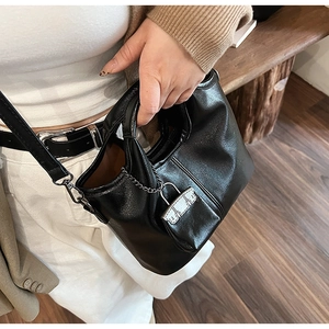 Dettaglio della borsa in pelle nera lucida con texture stropicciata e lucchetto con catena