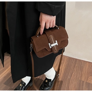 Détail du sac bandoulière en daim marron avec rabat festonné et boucle en métal argenté